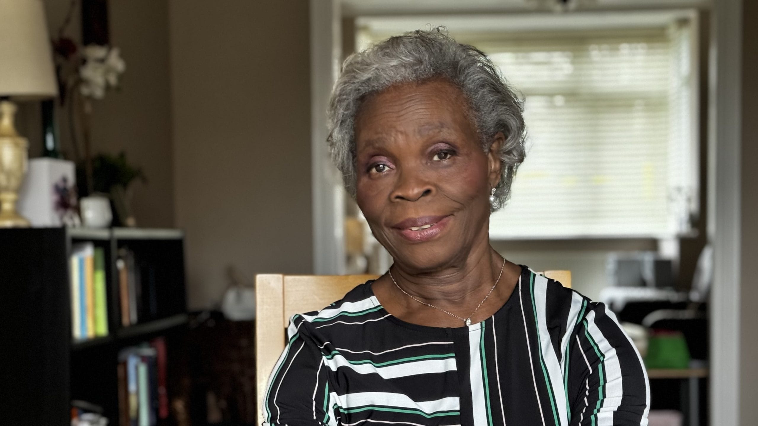 Headshot of Charlotte Osho, member of NHS Retirement Fellowship Newham branch, dressed in a stripped shirt and smiling directly at the camera