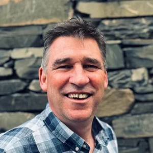 Headshot of Mike Seaton, CEO of the NHS Retirement Fellowship smiling and standing in front of a blurred outdoor background