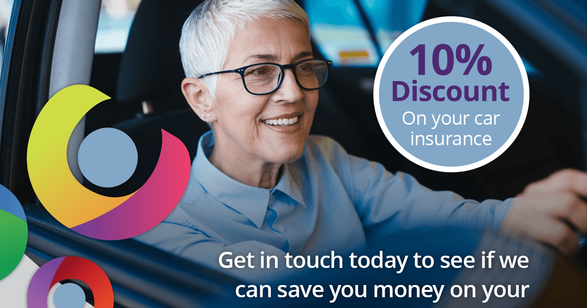 Picture of an older lady with glasses sitting in a car. She is smiling as she drives as the image is a promotional advert for CSIS car insurance for older people.